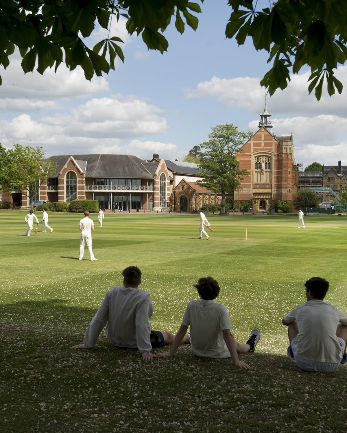 Boys watching school cricket on a summer pitch